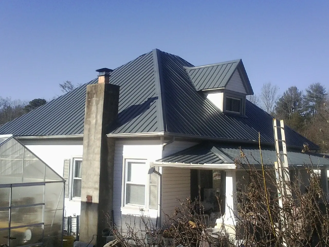 Dark blue standing seam metal roof on a white farmhouse with dormer — Slate & Tile Roof Repair by Roofing Brothers in Northumberland