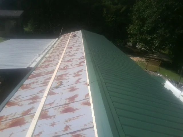 Old rusted panels beside newly installed green metal roofing — Wind Damage Roof Repair by Roofing Brothers in Northumberland