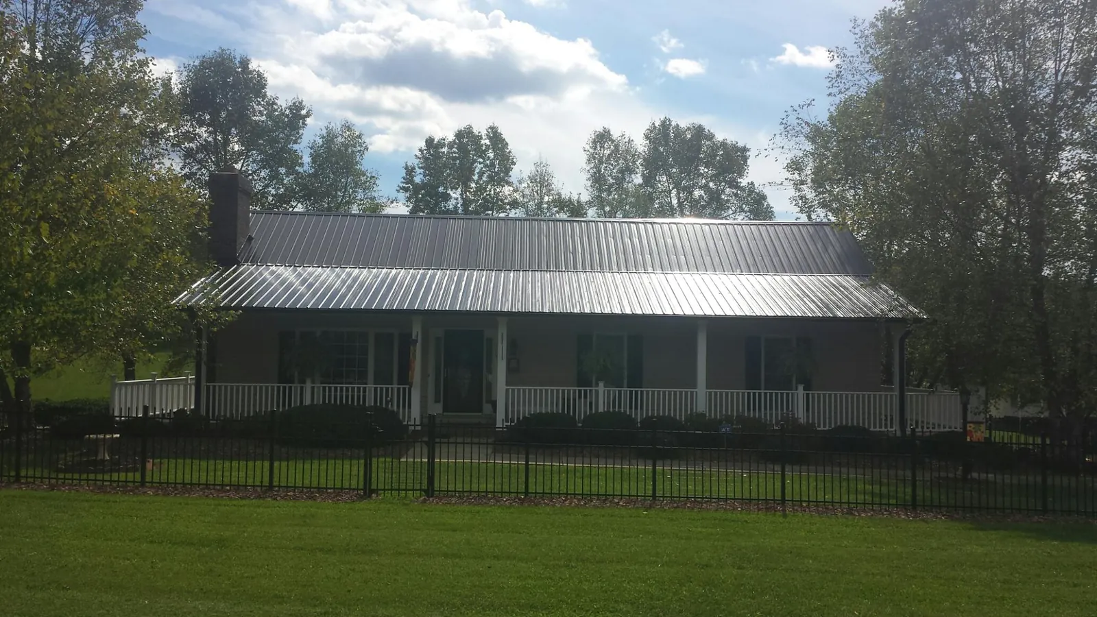Gray metal roof on a brick ranch with a full width front porch — Gutter Guard Installation work by our crew in Northumberland