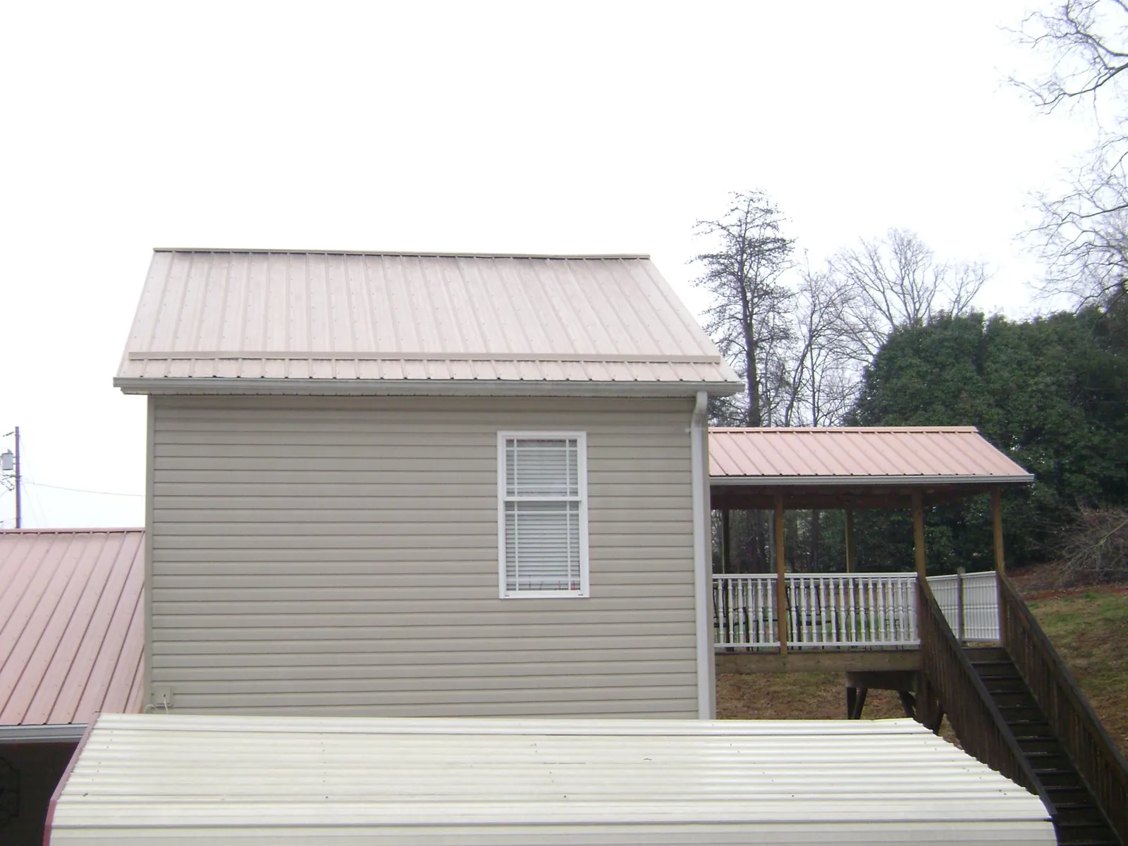 Tan metal roofs on a two story addition and attached porch, from a Roof Replacement job in Northumberland