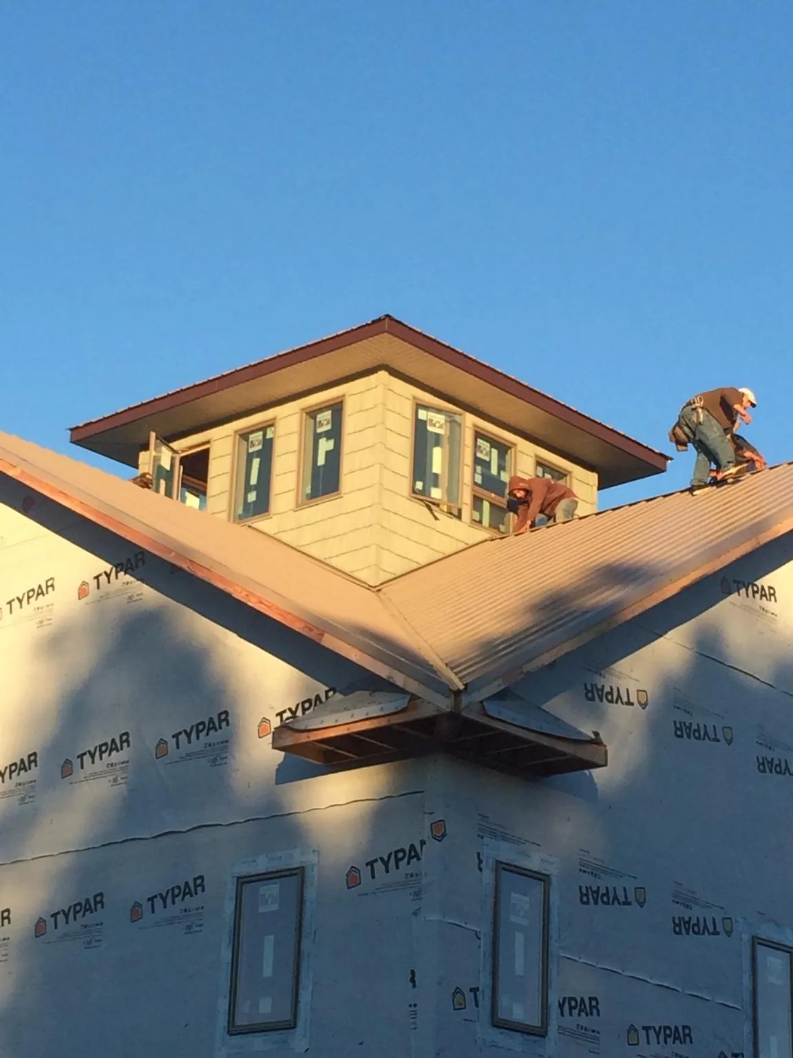 Roofers working around a rooftop cupola on a new metal roof at sunset — Roof Waterproofing in Northumberland by Roofing Brothers